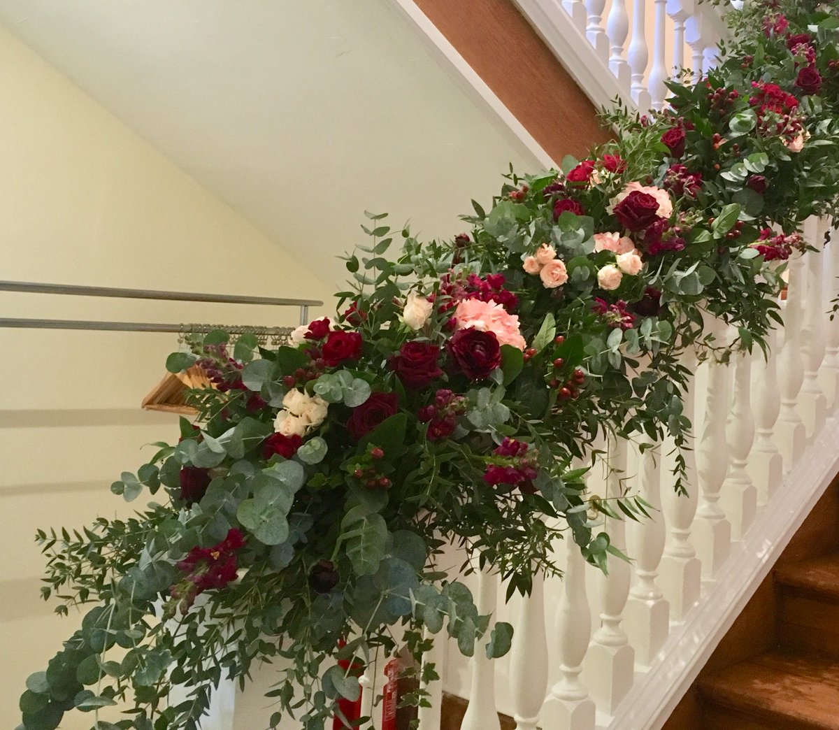 A stunning staircase garland in rich shades of burgundy and blush pink with lots of flowing greenery from a recent @BijouWeddings Notley Abbey winter wedding.  Complete with plenty of candlelight for warmth and glow.