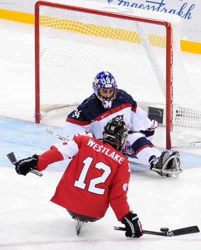 Paralympian Greg Westlake prepares to shoot the puck toward the net being guarded by an opposing goalie. (Photo Credit: Canadian Paralympic Committee)