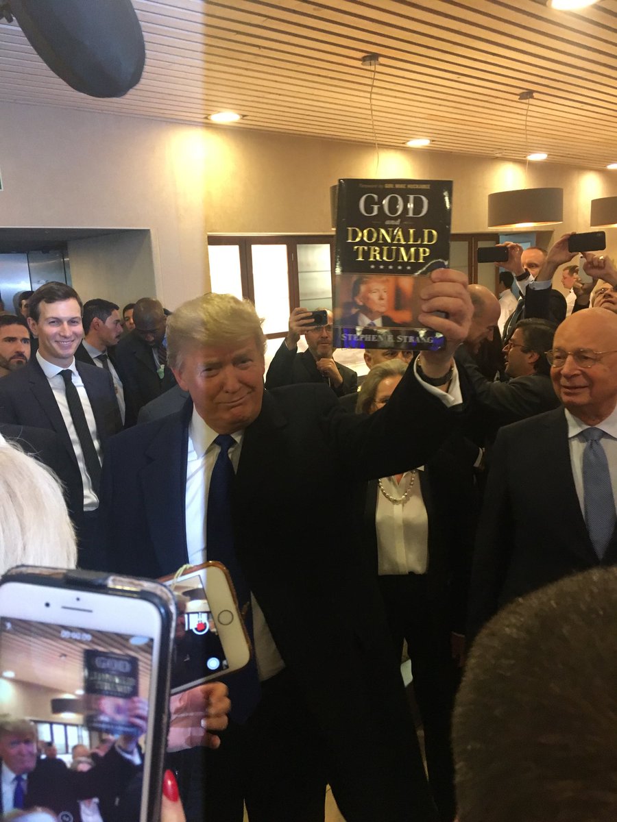President Trump holds up God and Donald Trump, a book written by Stephen E. Strang