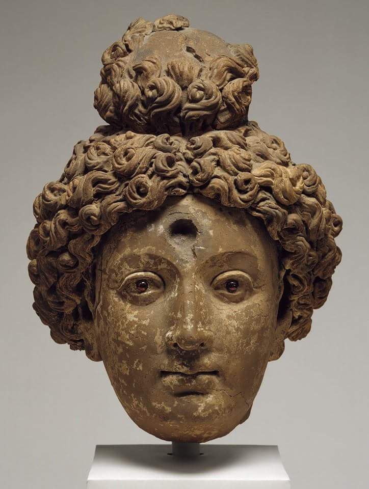 An exceptional 5th- 6th century clay head of a Buddha or Bodhisattva,with inlaid garnet eyes. Layers of clay were added over a core to build up the face, traces of the final white coat are visible on the cheek and forehead. From Afghanistan.