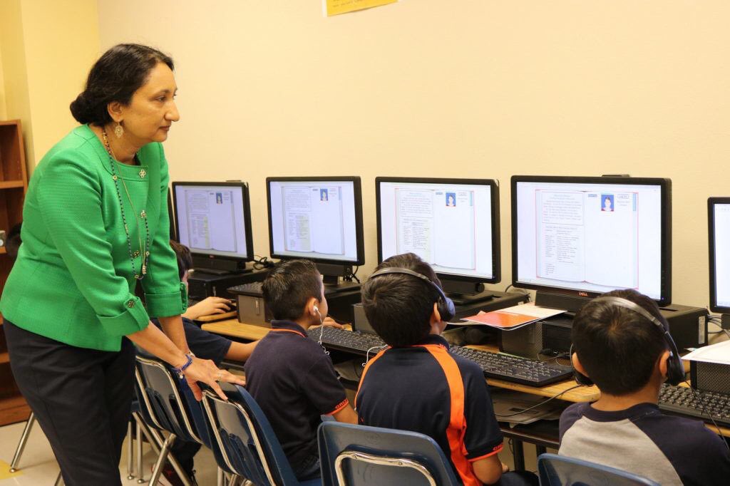 Woman helping children looking at computers