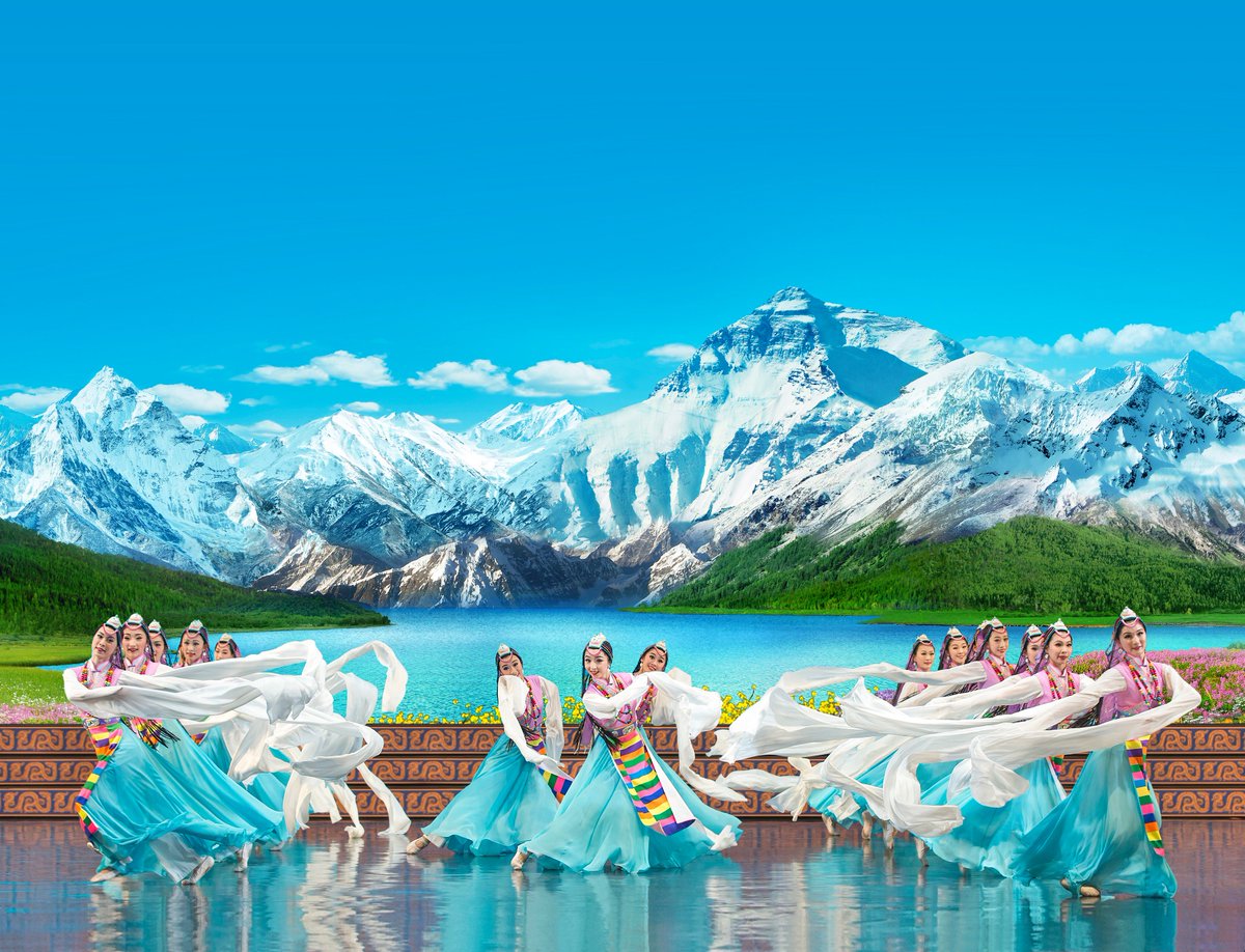 Performance photograph from Shen Yun - women dance in front of a Tibetan mountain backdrop