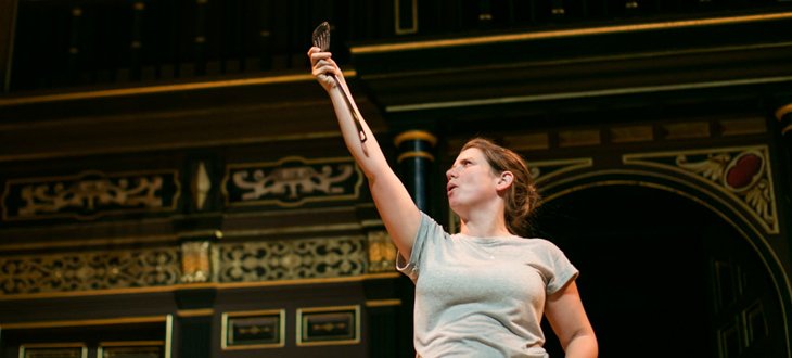 An actor holding a spatula in her hand in the air