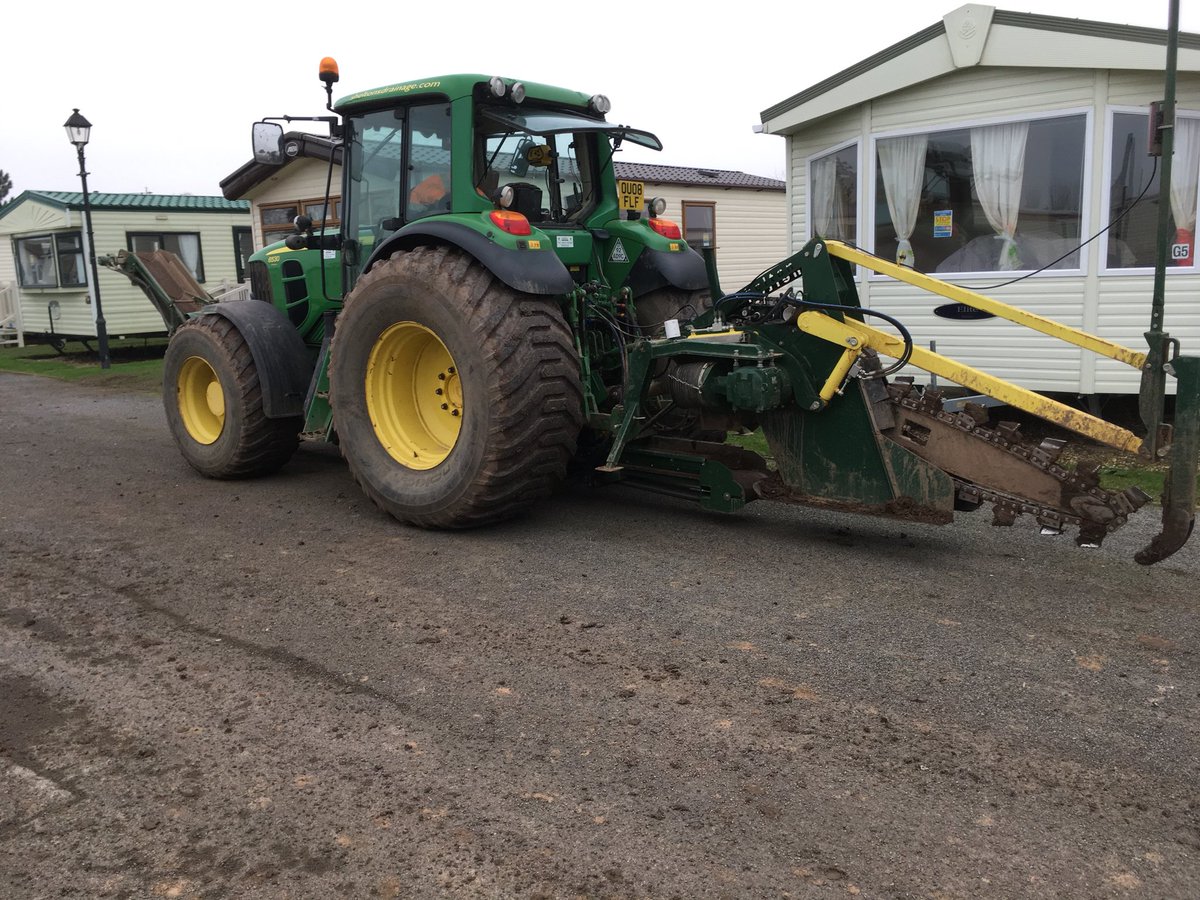 SheltonDrainage's tweet photo. There wasn't enough room for our CT100 Chain Trencher to get between 2 rows of caravans @Tomlinsonsleisurepark to install drainage, so we moved the side conveyor to the front of the tractor,then connected the trencher to it with additional conveyor running underneath the tractor https://t.co/SwGlH63Dte