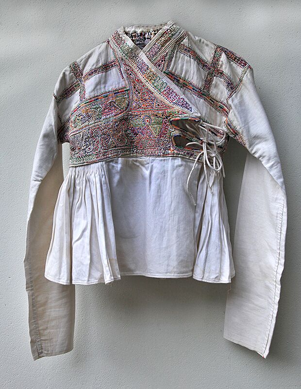 Decorated with motifs including peacocks, parrots, scorpions and florals – all considered to be auspicious - this smock, known as a Kediyun, is  worn by Dhebaria Rabari men in the Kutch district of Gujarat. It is made from heavy white mill cotton and hand and machine stitched