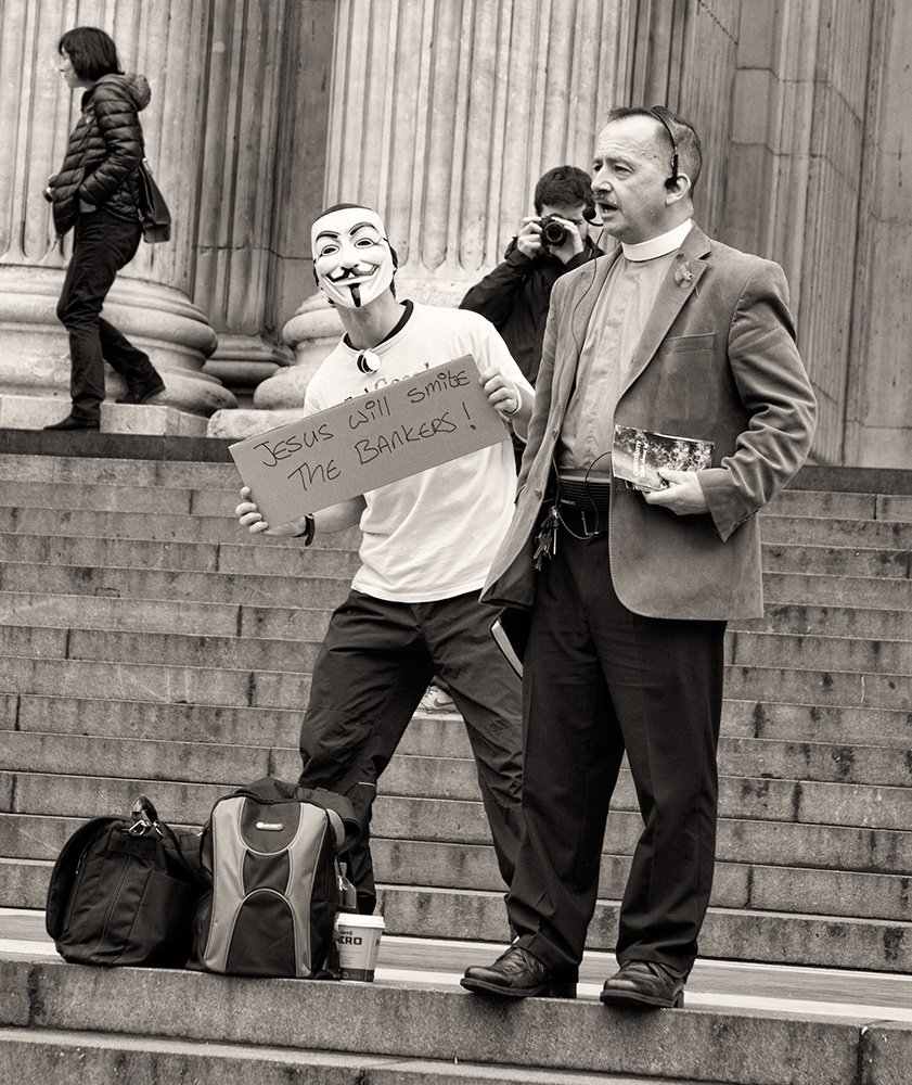 WayneAnthony88's tweet photo. I shot this during the Occupy takeover in St Paul's The priest was saying god would be on the bankers side so some lads from @4Chan_Anon gave him stick #OccupyLSX #Anonymous #PhotoJournalism #WayneAnthony https://t.co/if4tzTxSni