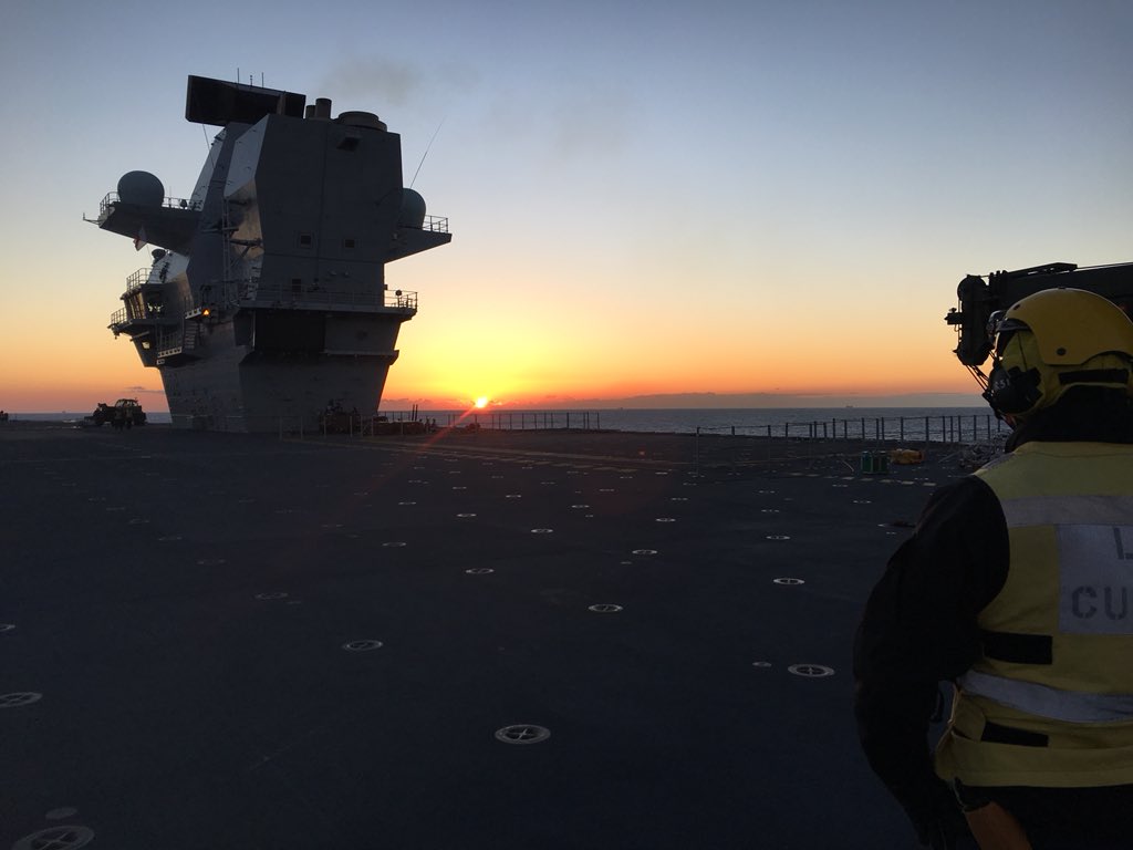An aircraft handler gazes at the sunrise