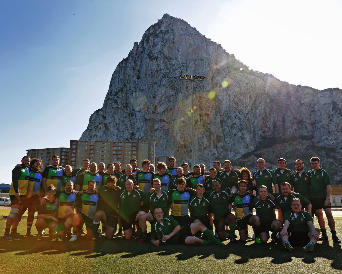 Group picture of both teams in front of the rock.