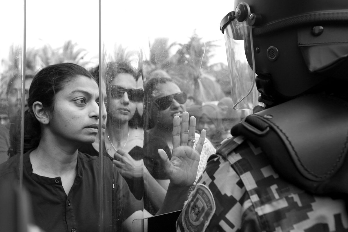 AshwaFaheem's tweet photo. Maldives Parliament member @evattey standing in front of policemen holding shields today during the protest that was held to call out for the implementation of the Supreme Court order. #photojournalism #MaldivesIncrisis #mvprotest #Al @AlJazeera_World @reuterspictures #media https://t.co/IGjSiUA6Nh