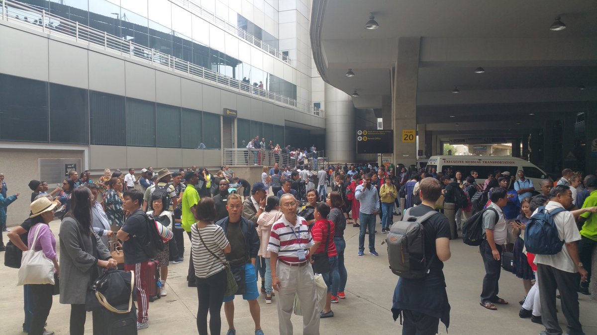 #ORTambo #International #Airport emergency evacuation. All of us now standing outside of airport terminal buildings. More people are laughing now. Most just continue with general discussions. Still no clarity on official reason for evacuation. #ORTevacuation