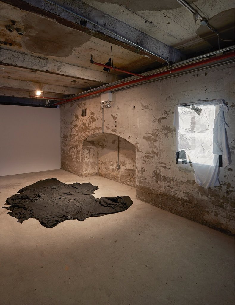 sculpturecenter's tweet image. Works by Lachell Workman on view through April 2 as part of #InPractice. [Left] 'Untitled, To be Cloaked in Black.’ Asphalt, T-shirts. [Right] 'Hold Me Down, a Litany.’ T-shirts, 35mm slide projector, slides. Works courtesy the artist. Photo: Kyle Knodell #anotherecho