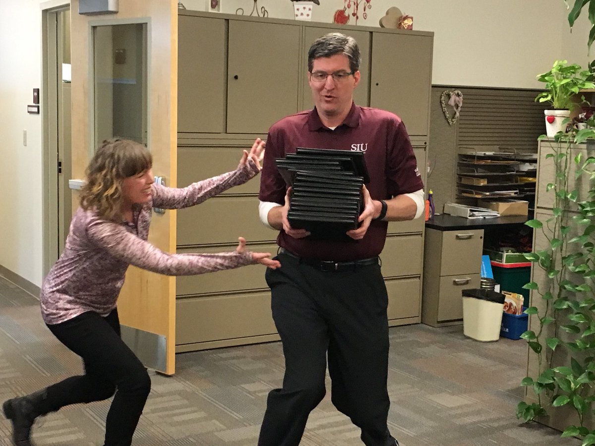 SalukiSpirit's tweet photo. On #SalukiFriday at the offices of the @SIUC_GradSchool, we thought that we might be able to grab ourselves a few diplomas, but we seem to be having trouble with the weight of the, stack as Admissions &amp; Records Rep Pamela Kelley tries to lend a hand… 

#WeAreAllSalukis https://t.co/fWB9ZQxniZ