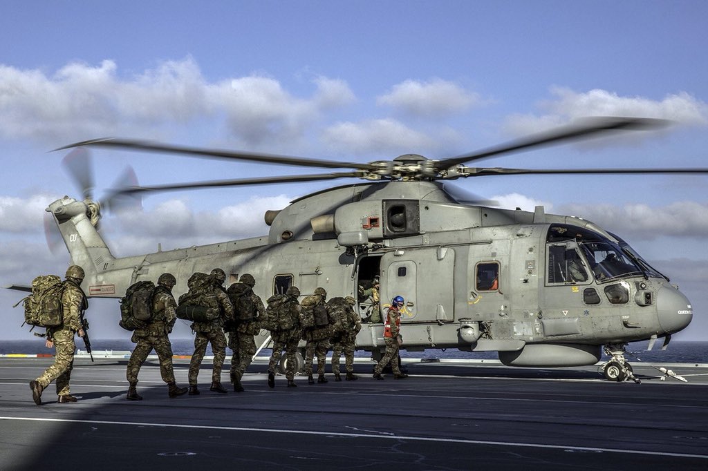 A troop of Royal Marines crossing the flight deck to get into a helicopter.