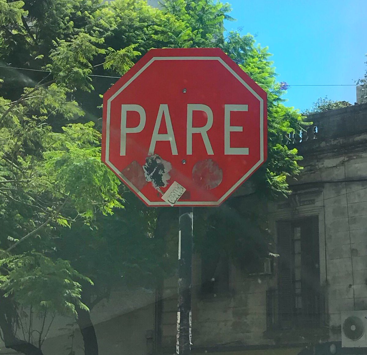 PARE viene de PARAR que significa DETENERSE. PARE es un semáforo en ROJO, y hay muchos carteles de PARE en la ciudad, aunque muchos no los vean. Suelen estar en las esquinas antes de cruzar. Parecen un adorno, pero no lo son. Están para ser respetados, aunque tengas la mano.