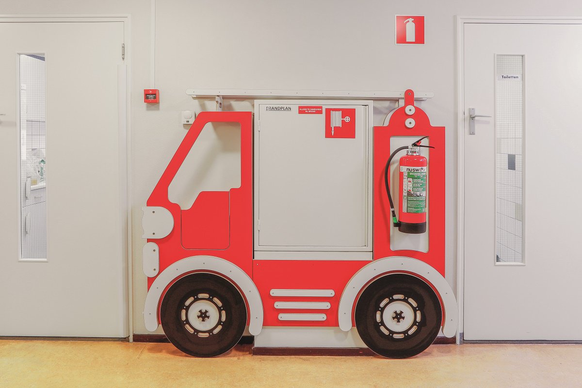 Complete restyling door camouflage. Want een brandslang ziet er niet kindvriendelijk uit, maar is wel noodzakelijk. Daarom hebben we hem op speelse wijze verwerkt in de vormgeving van de gang.