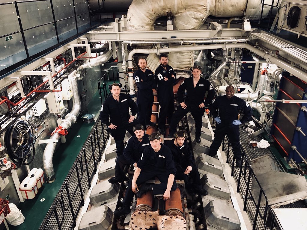 A very large engine with 8 engineers standing and sitting on it.