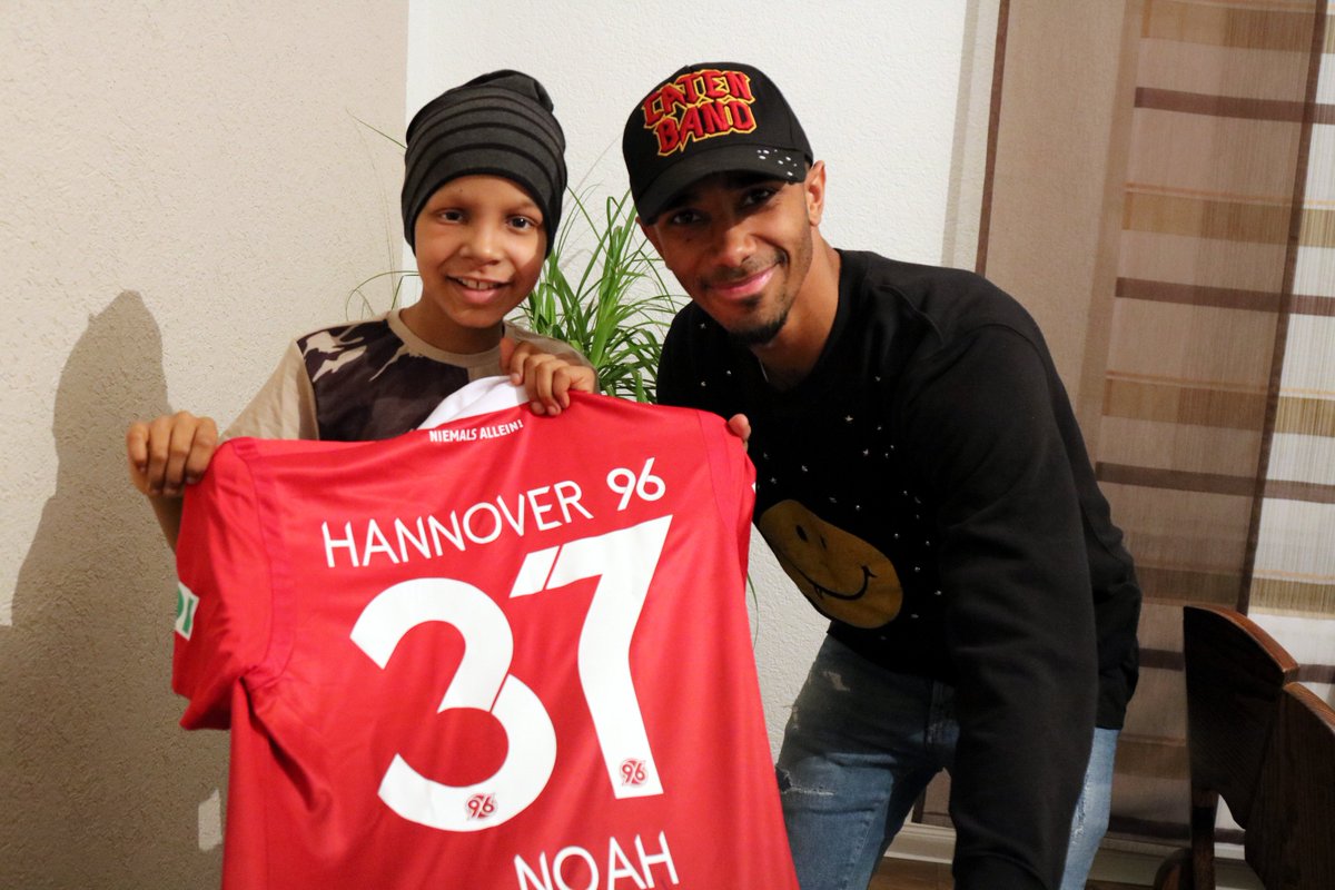 Hannover96's tweet photo. Der an Krebs erkrankte kleine #H96-Fan Noah hat einen HERZENSWUNSCH: Er möchte noch einmal mit seinen Eltern und seiner kleinen Schwester seine Familie in Nigeria besuchen. @noahbazee will ihm dabei helfen und hat ihn besucht: 👉 https://t.co/nUYBaAPg8D! #NiemalsAllein ⚫️⚪️💚 https://t.co/Kbe3HqUV3e