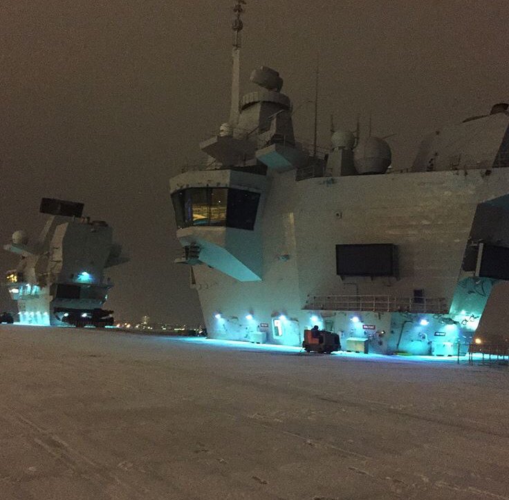 An early morning view of the aft island in the dark. Flood lighting shows the small amount of snow on the flight deck.