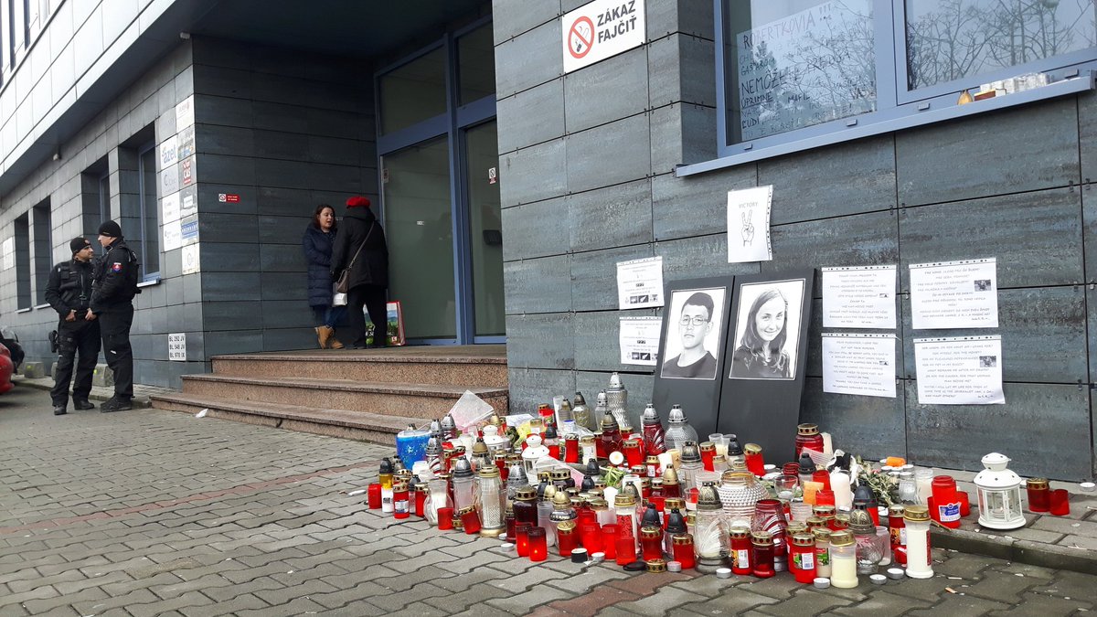 Miejsce pamięci po zabójstwie dziennikarza Jana Kuciaka i jego narzeczonej przed budynkiem <a href="/RingierAxelSpri/">RingierAxelSpringer</a> w #Bratysława #Słowacja. W głębi uzbrojona policja pilnuje wejścia do budynku. #allforJan