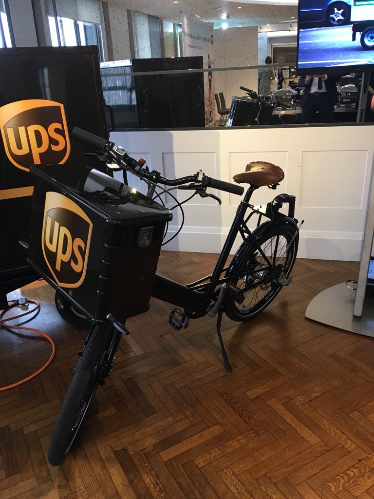 UPS_DE's tweet photo. A Sustainability concept has various parts. At the Sustainability Summit in London #EconSustainability see another way to deliver packages: an electric trailer and a bike. Only the driver is missing today. This works. Promise. @UPS_News https://t.co/Pwi4kpceYD