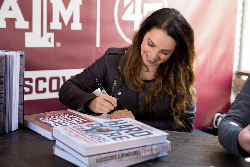 Jess Pryles signing her book in front of maroon banner