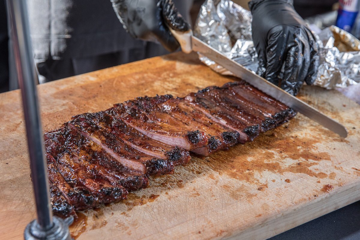 A rack of smoked pork ribs being sliced