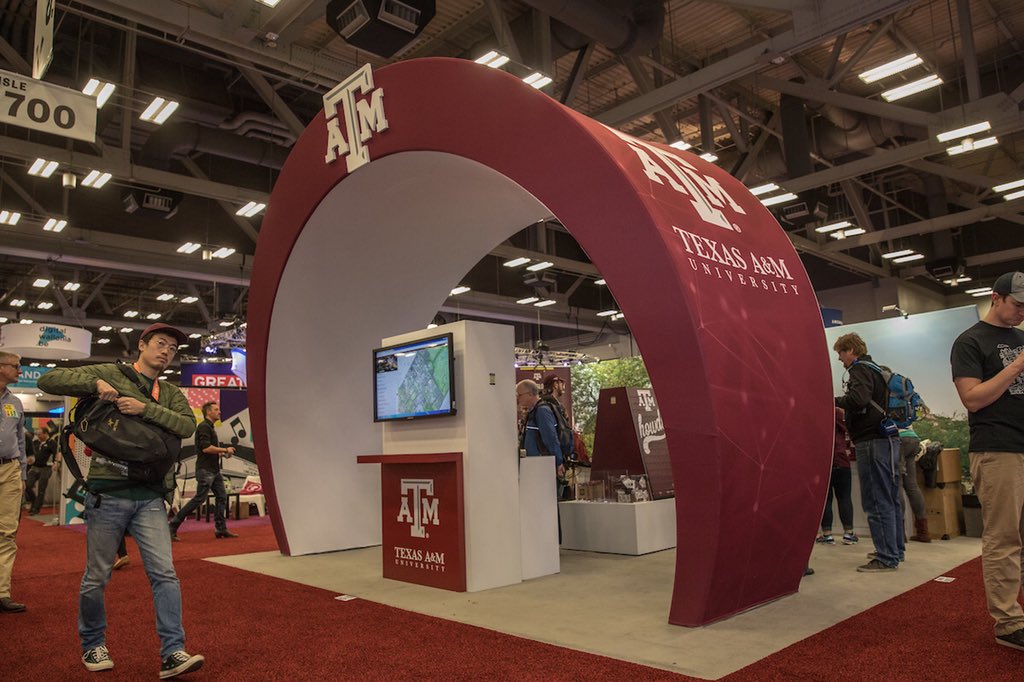 Texas A&M Booth in the shape of a ring at SXSW trade show with people walking around