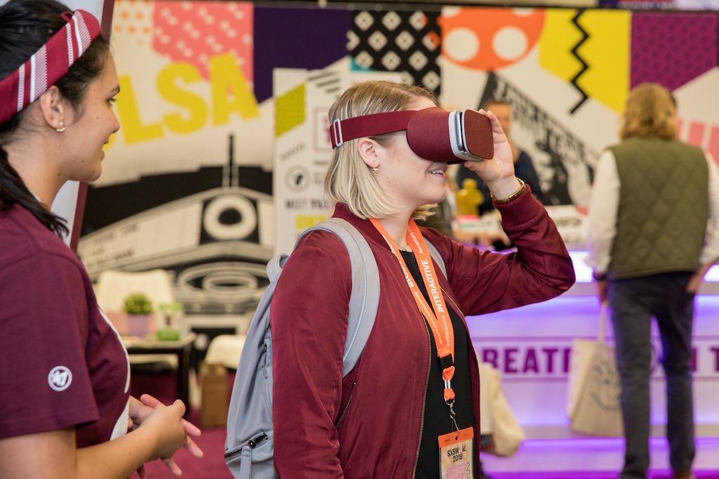 Woman in maroon using maroon VR goggles at Texas A&M Booth