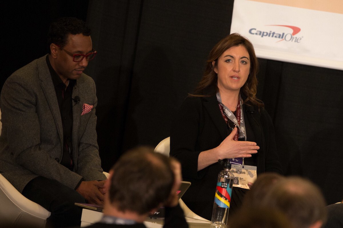 Two speakers sitting on stage with attendees in the foreground