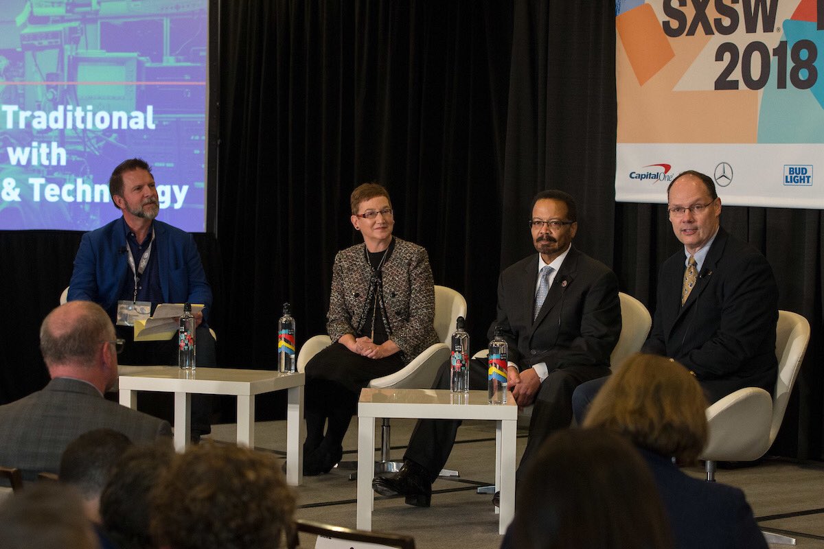 Four speakers seated on stage in front of SXSW banner