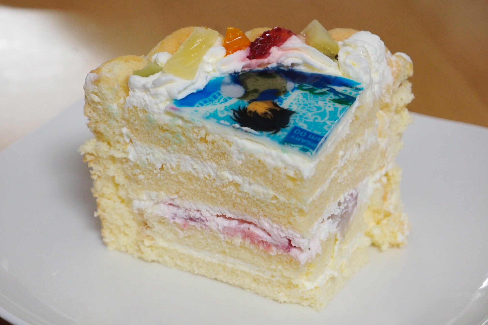 よっくん 機動戦士ガンダム00 10th Anniversary ケーキセット 断面はこのようになっています フルーツ は下段のみ スポンジはややしっとりしていて食べやすく 全体として甘さはほどほどに イラストがプリントされている白い板はチョコではなく