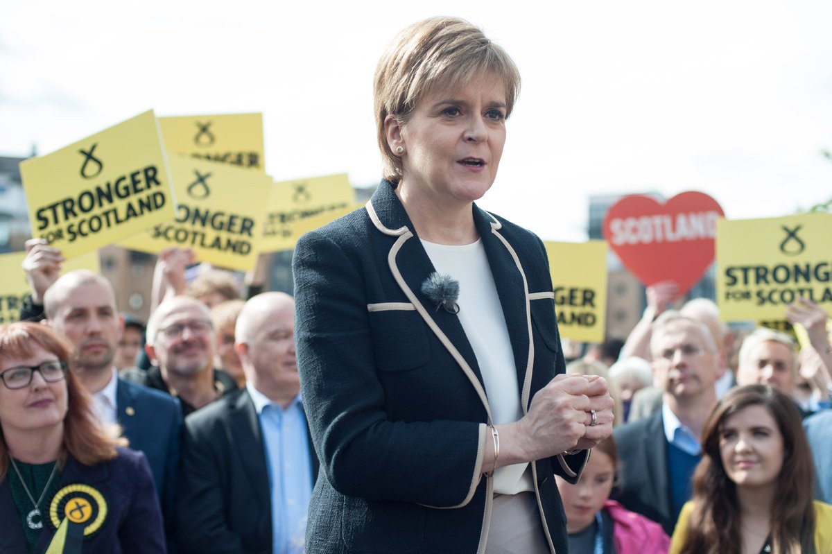 A photograph of Nicola Sturgeon surrounded by activists. Some are holding up placards that say 'Stronger for Scotland'.