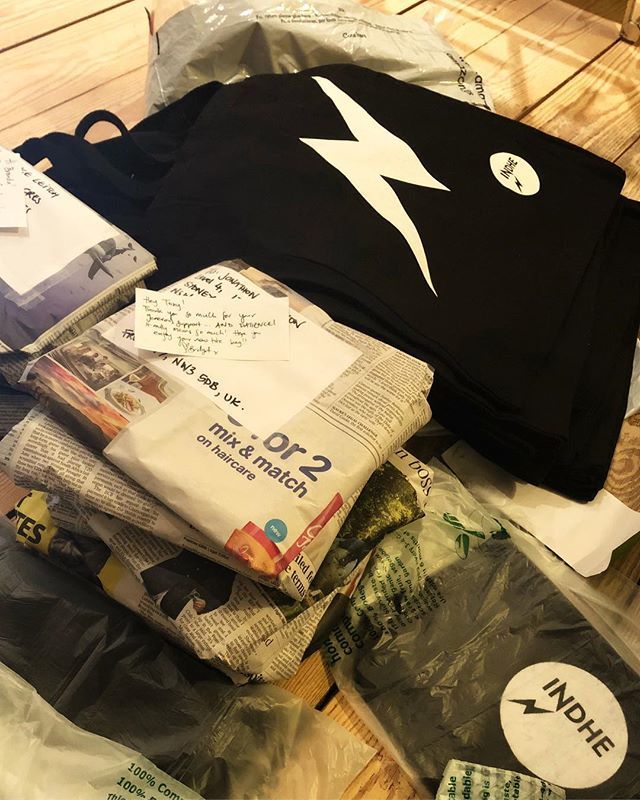 INDHEartists's tweet photo. A batch of INDHE merch packaged up for postage. In compostable bags and newspaper, because packaging SUCKS. ⚡️⚡️⚡️ https://t.co/u4dni2N4Mh