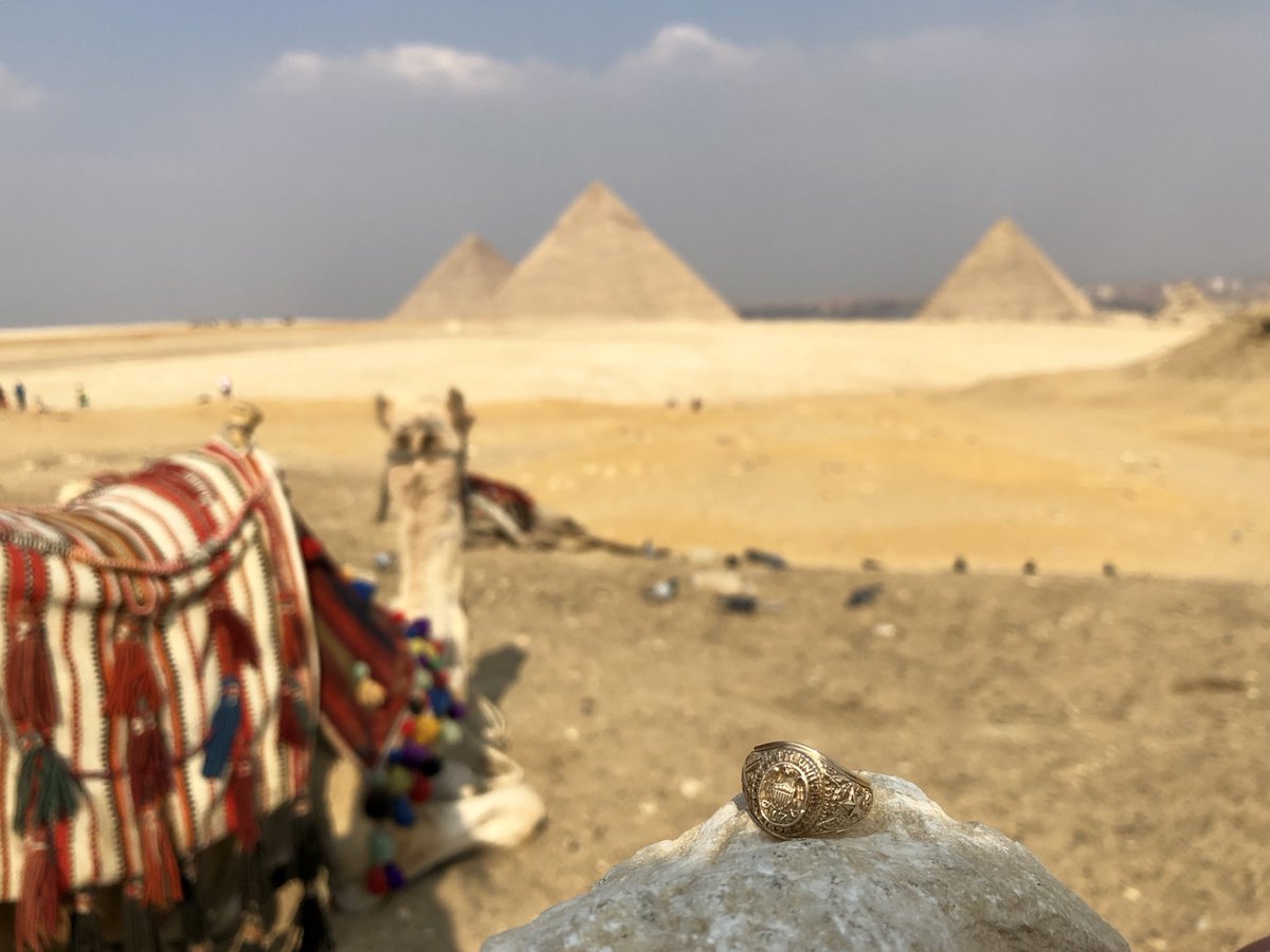 Aggie Ring in the foreground with a nearby camel and Egyptian pyramids in the background