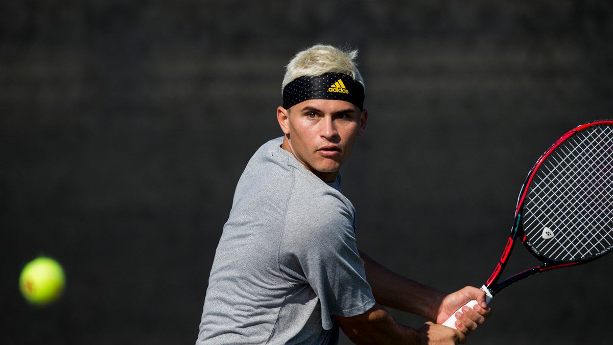 photo of tennis ball flying at an aggie men's tennis player preparing to hit it with his racket.