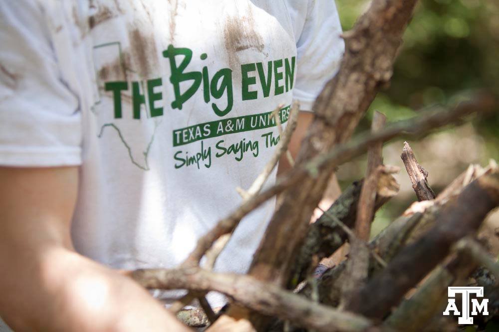 person wearing white big event shirt carrying sticks