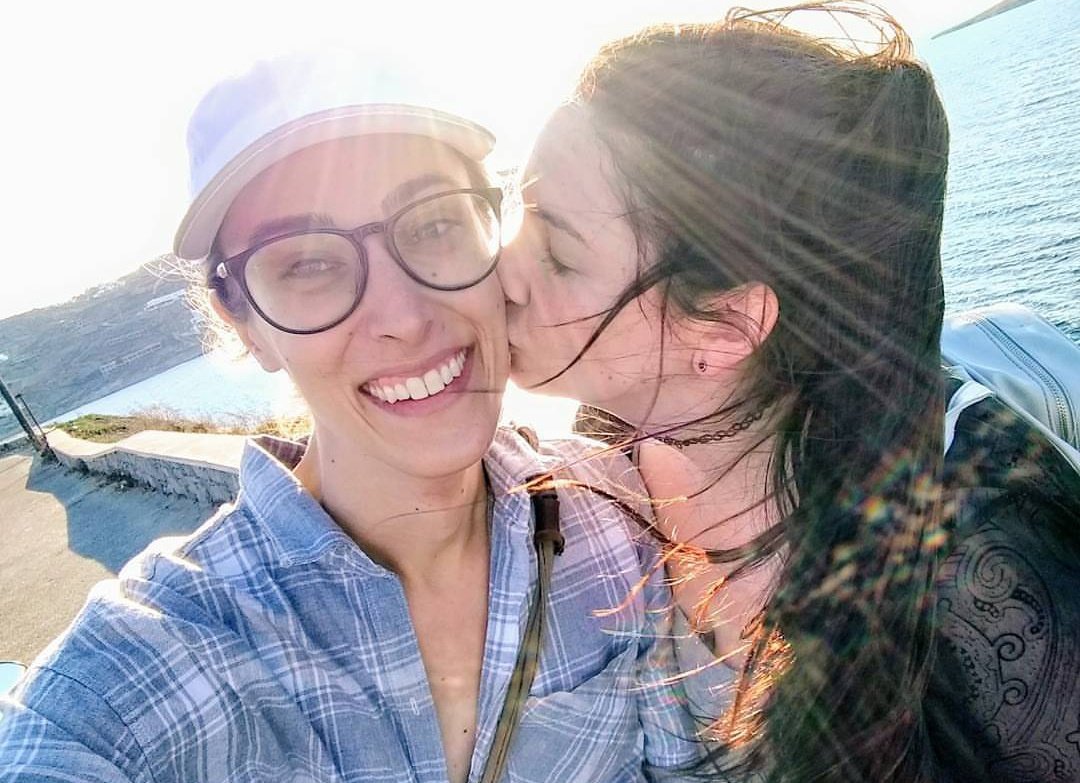 Fiona kissing Riley on the cheek with the sun shining in from the background.