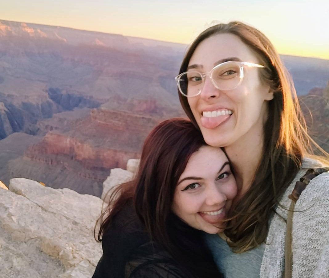 Riley holding Fiona while they both smile and the Grand Canyon is in the background.