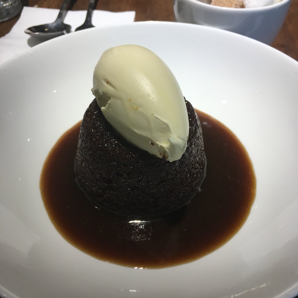 Sticky toffee pudding with cream on top.