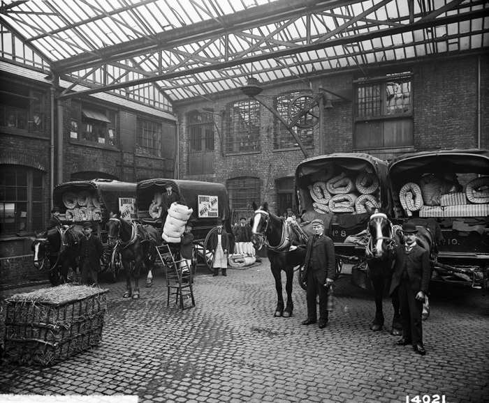 Heals_Furniture's tweet photo. On the 25th March 1897 - exactly 121 years ago today - Heal and Son Ltd staff posed for this photograph in our courtyard on Tottenham Court Road. The horse-drawn wagons are loaded with mattresses and bedding made at the site where we still work to this very day https://t.co/3hW4h1DPRz