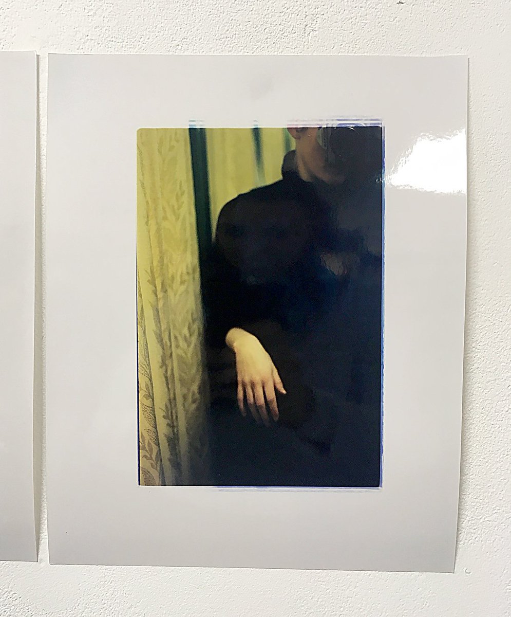 Colour photographic print depicting a self portrait taken in a mirror. Subject's hand and patterned curtain are the main feature of image.