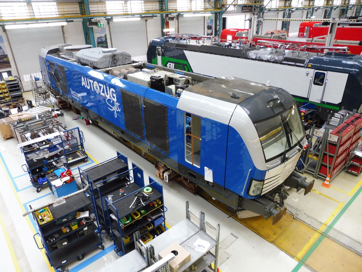 SiemensDE's tweet photo. Exklusiver Blick auf ein blaues Kraftpaket: Die im @SiemensMobility Werk Allach im Bau befindliche hochmoderne Vectron-Lok kommt demnächst auf einer der beliebtesten Zugstrecken D.'s zum Einsatz: dem Autozug nach Sylt ... Wer mitfahren möchte: https://t.co/SXB7eAZL31 https://t.co/Y73ttvi05k