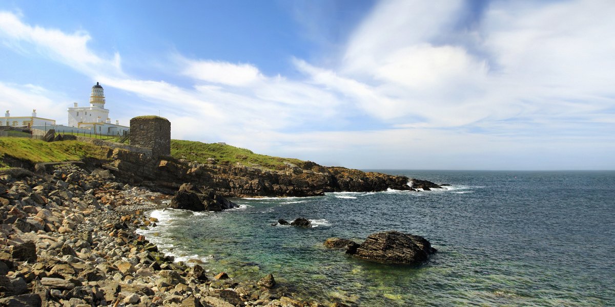 Aberdeenshire coastline - lighthouse on a rocky coastline with the water rolling in.