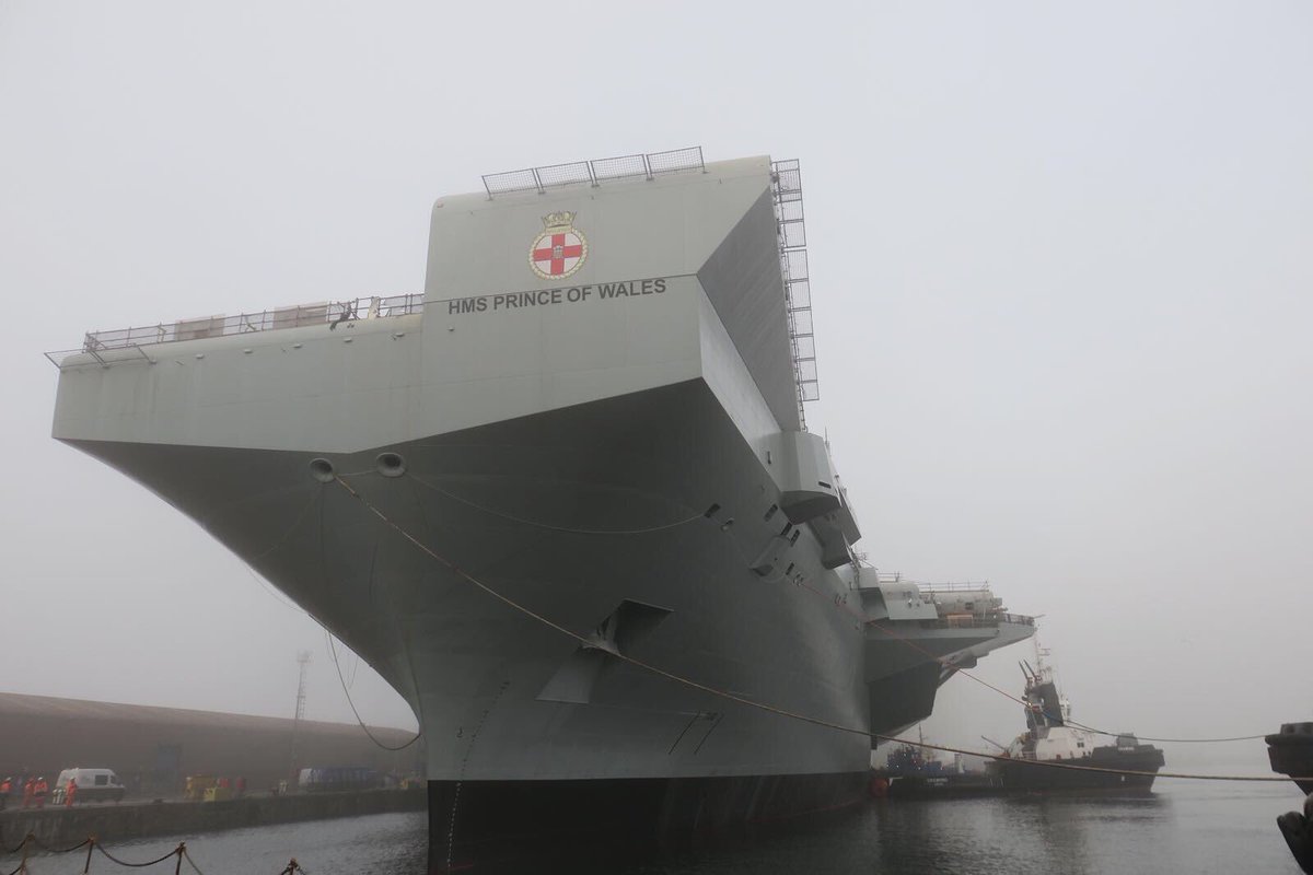 HMS Prince of Wales afloat and being moved to a basin by tugs.