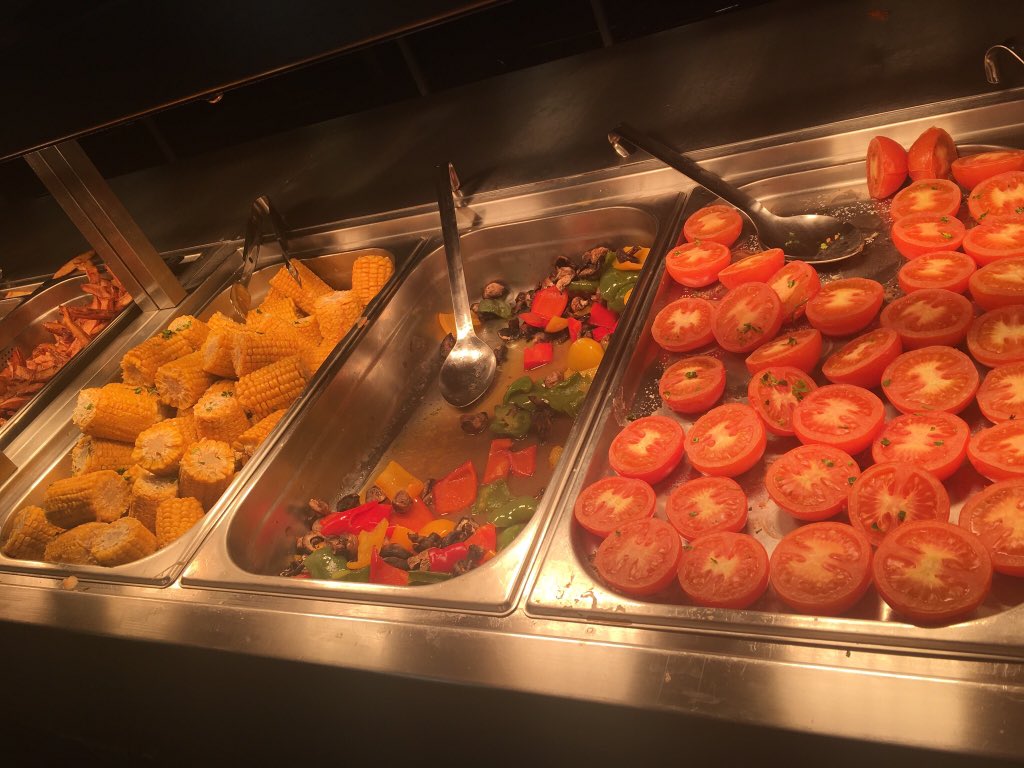 Serving trays filled with corn on the cob and other vegetables.