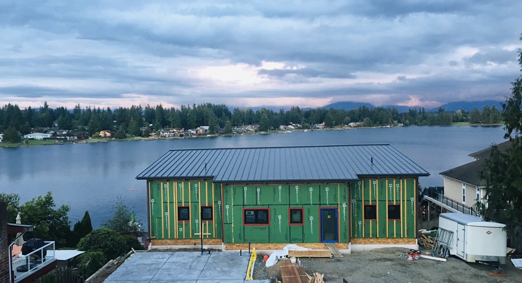 LMPassiveHouse's tweet photo. Love the way the metal roof seems to blend in with the water from my neighbors deck. Garage is up now and coated with @PROSOCO #Cat5 and should be getting the roof next week! https://t.co/YxsCN9BiWD