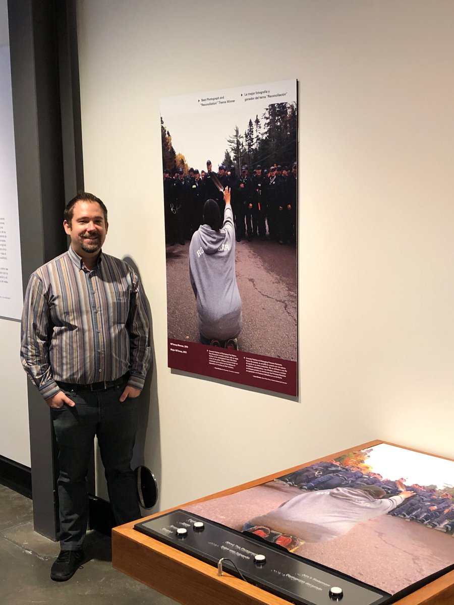 A man standing by a photo and a tactile stand.