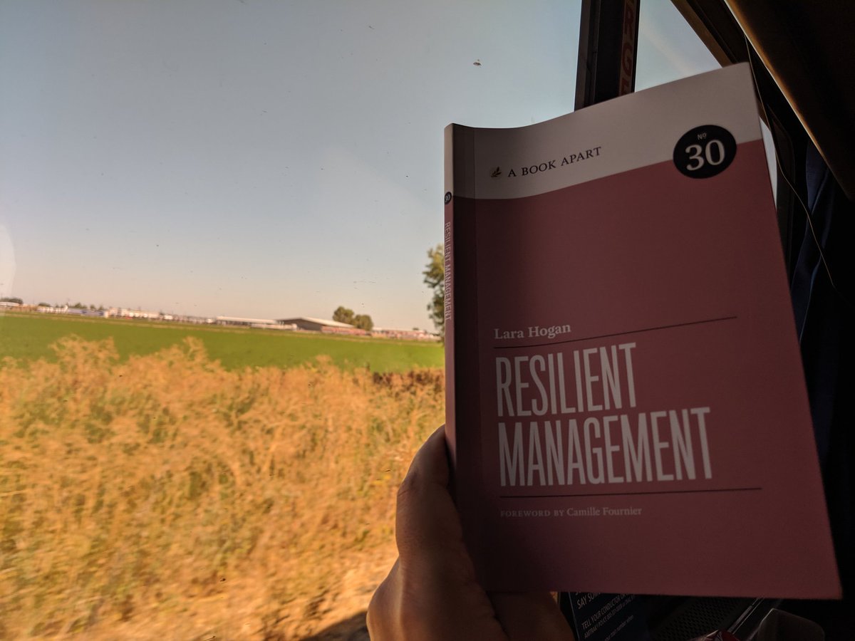 Lara Hogan's book Resilient Management with a field in the background.