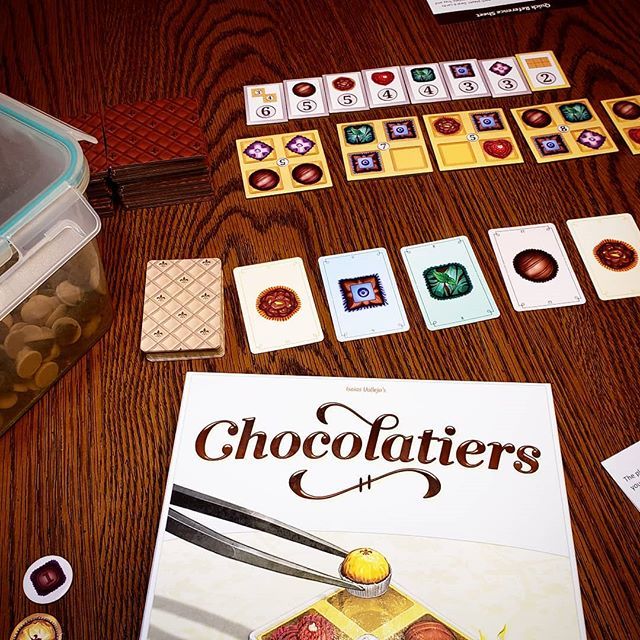 BoardGamerSteph's tweet photo. Chocolatiers from @_dailymagicgames_ is a delight. Chocolates not included, sadly. 🍫 bring your own! Tasty. #chocolatiers #dailymagicgames #chocolate #bgg #allthegames #gencon #boardgamegeek https://t.co/icstzpfMmg https://t.co/9YWeANCxW7