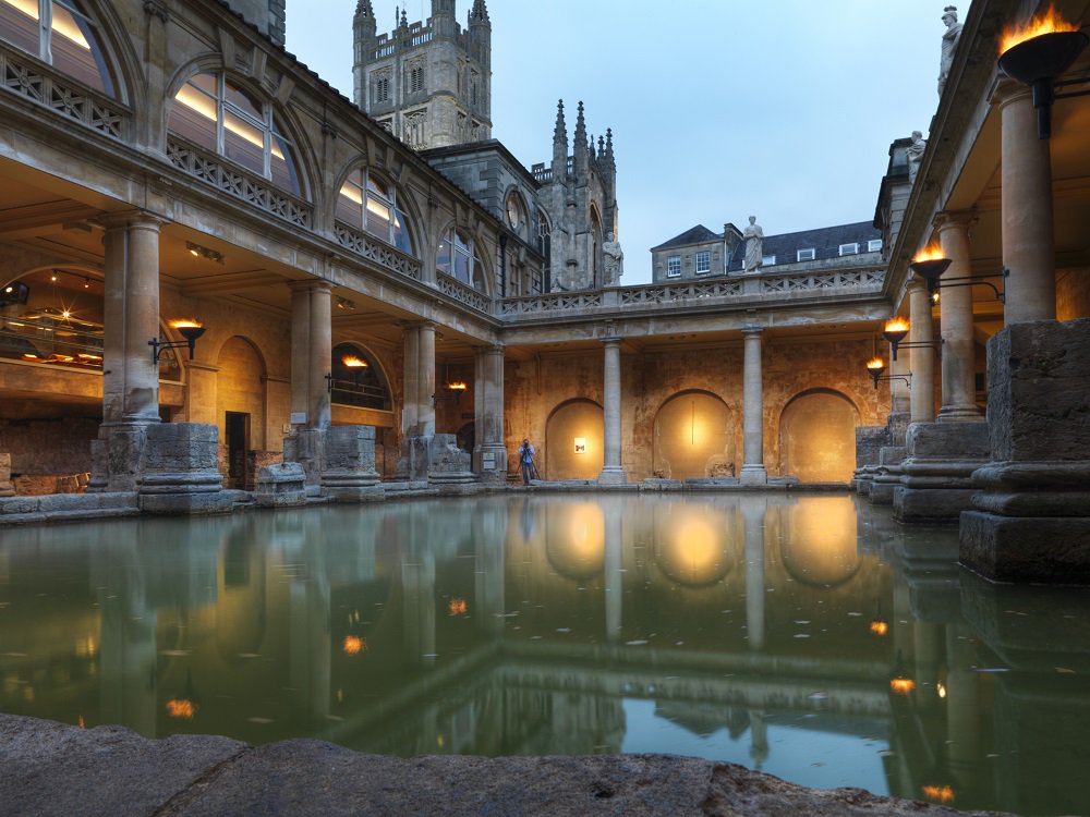 VisitBath's tweet photo. Experience the @RomanBathsBath by magical, flickering torchlight and enjoy three delicious courses at the @RomBathsKitchen with our Torchlit Visit and Dinner Package. 🕯️♨️ > https://t.co/iaYY3FfVPW https://t.co/GpaU4xSaWu